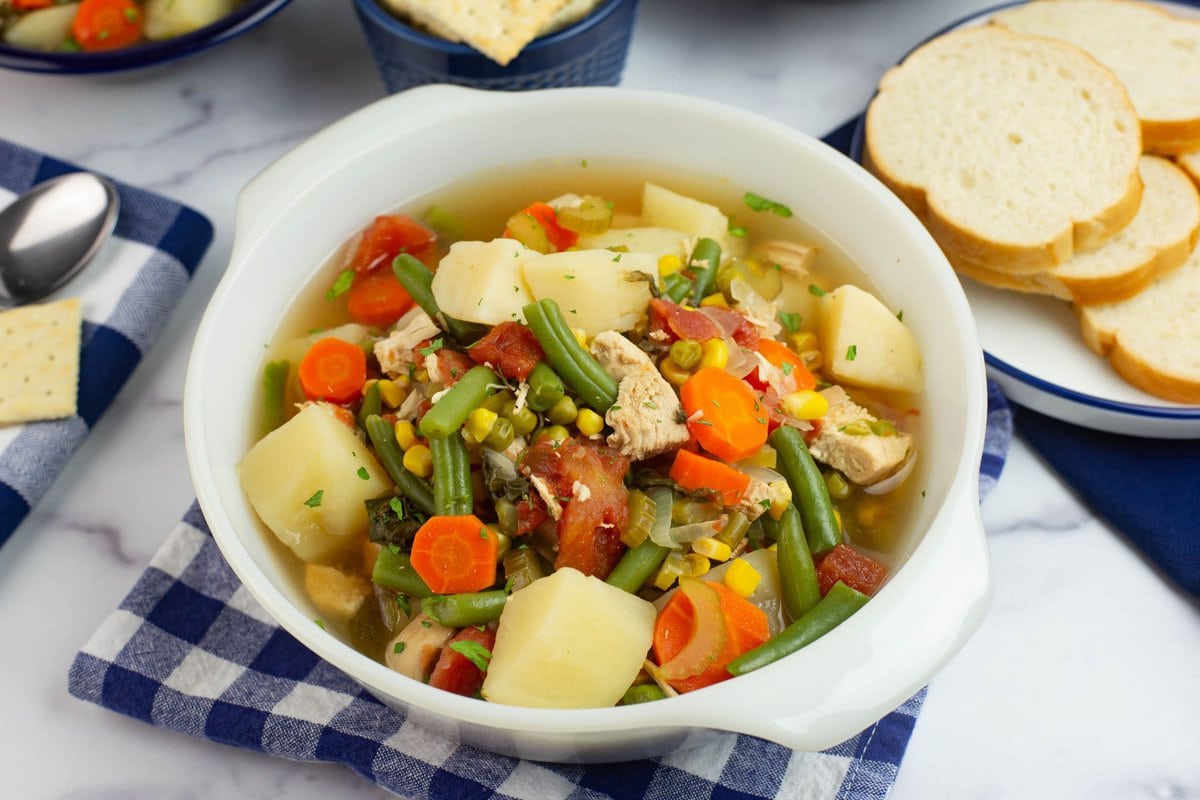 Hearty chunks of chicken and vegetables in a rich broth in a white serving bowl.