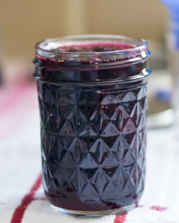 A jelly jar filled with blueberry jam.