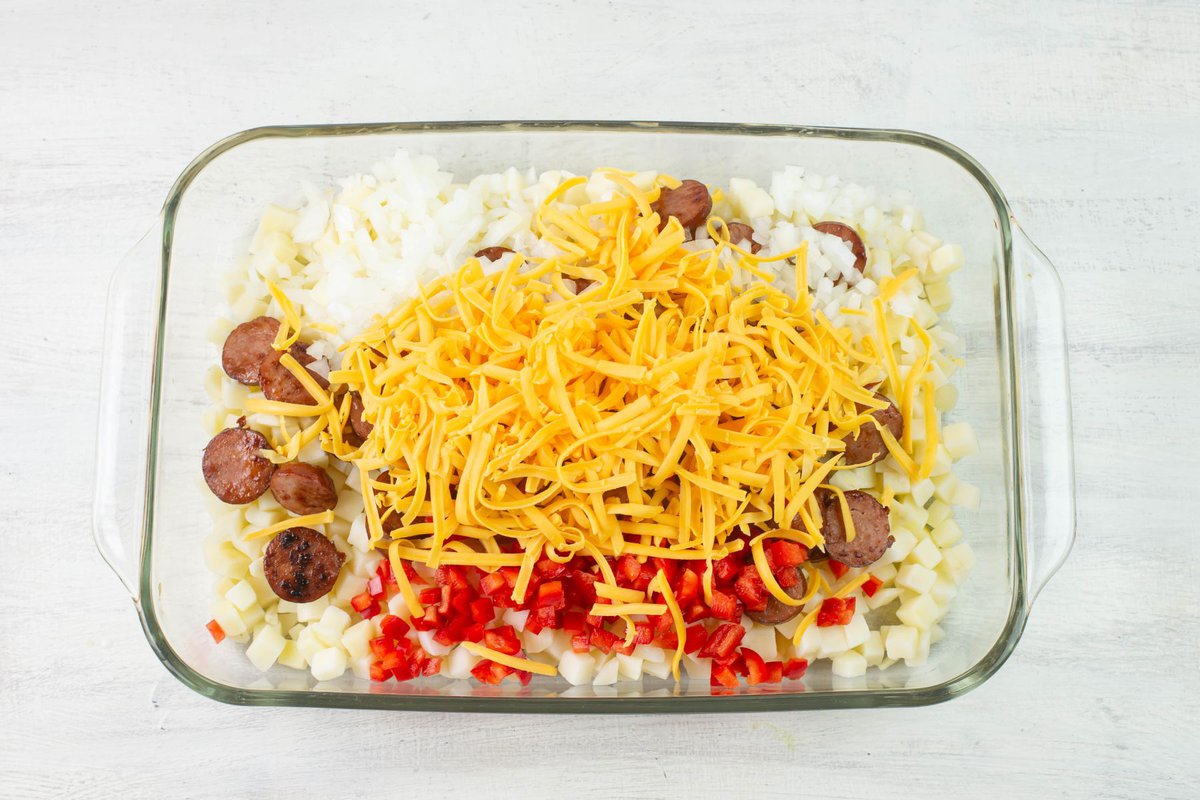 Mixing sausage, hash browns, cheese and vegetables in casserole dish.