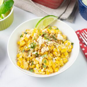 Mexican Street Corn Casserole served in a bowl garnished with lime wedge and cilantro.