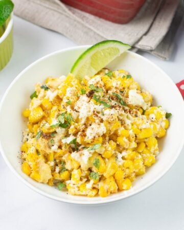 Mexican Street Corn Casserole served in a bowl garnished with lime wedge and cilantro.