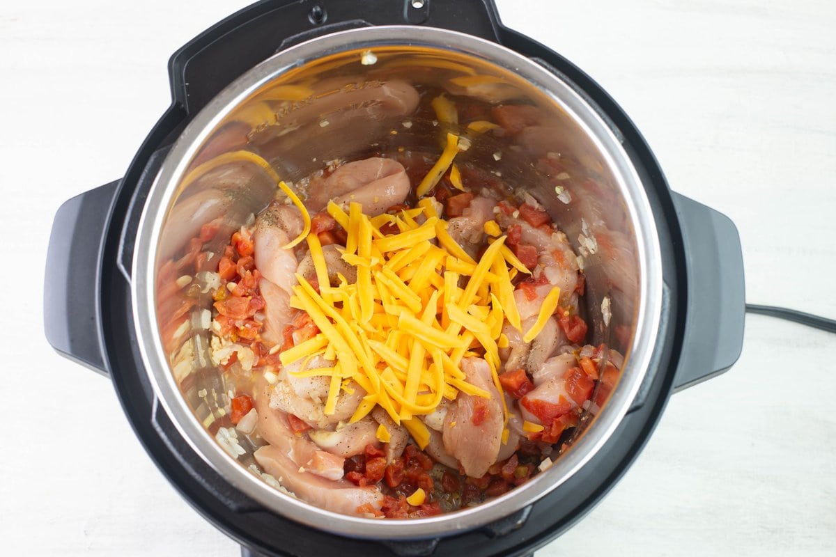 Layering the chicken, rotel, and cheddar cheese in the pot.