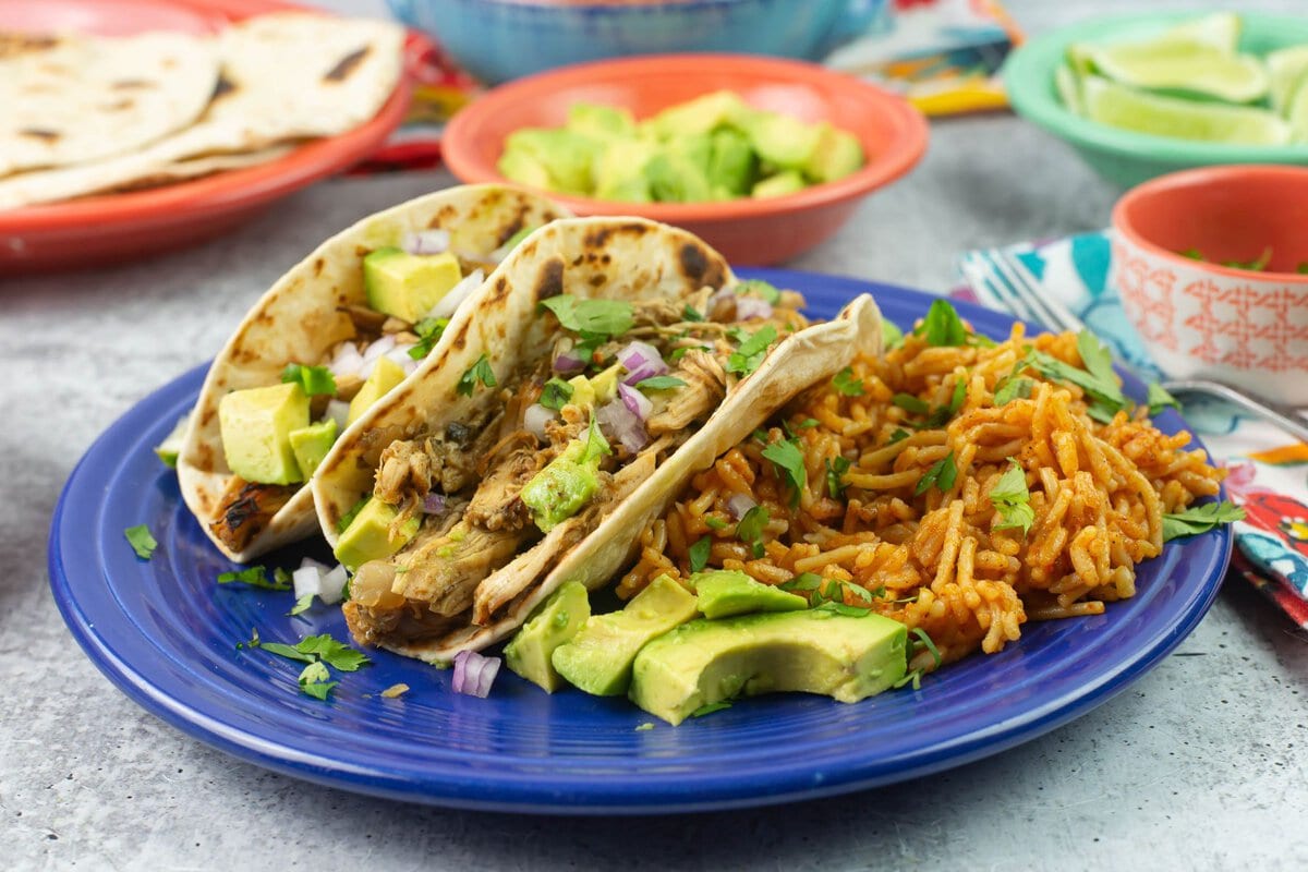 Serving shredded chicken carnitas on a dinner plate with all the toppings.