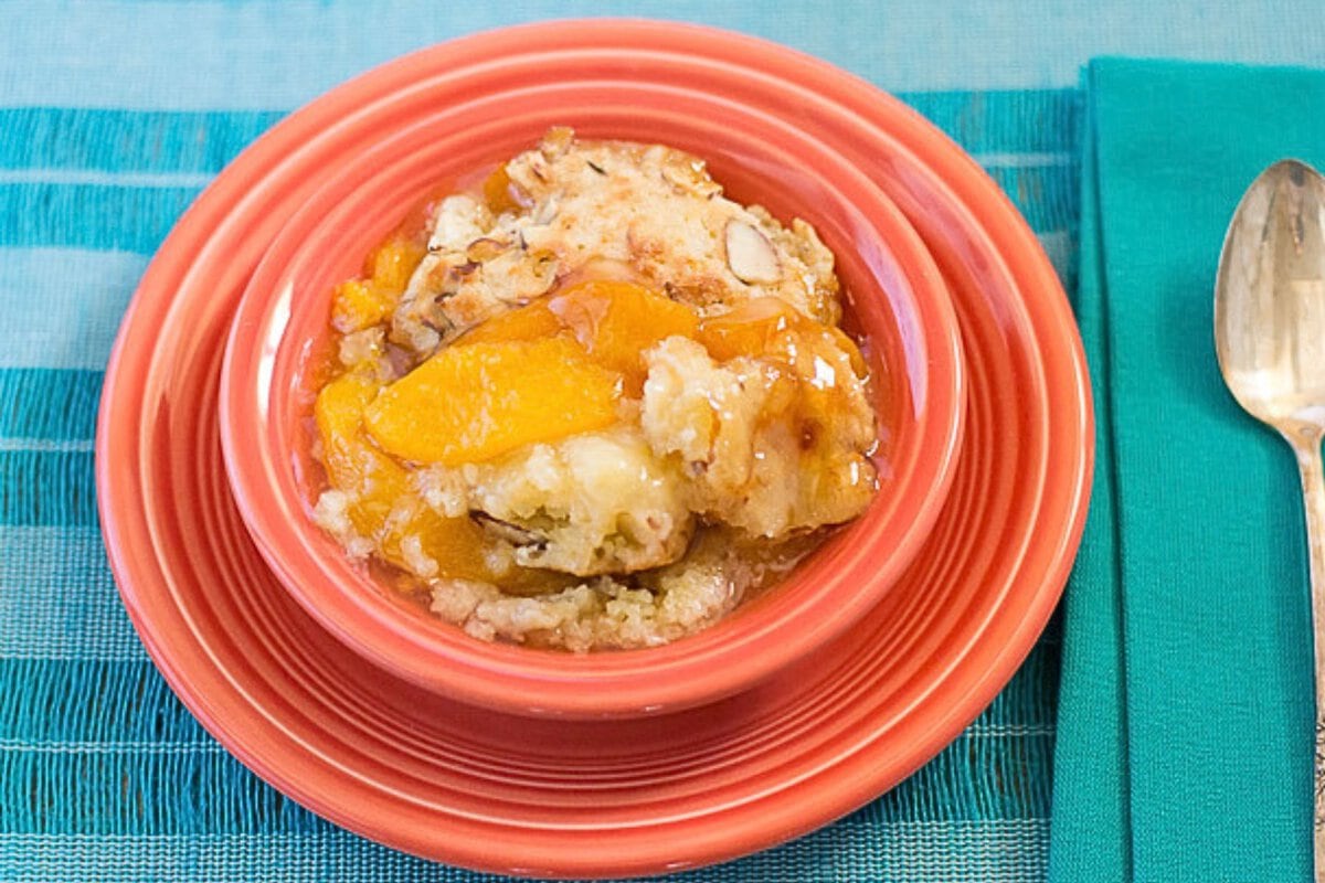 Peach cobbler served in a dessert bowl with a spoon.