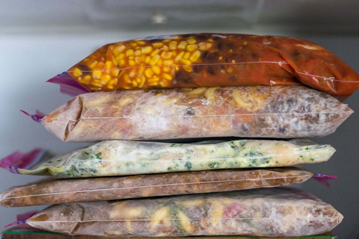 5 frozen freezer meals in bags inside a freezer.