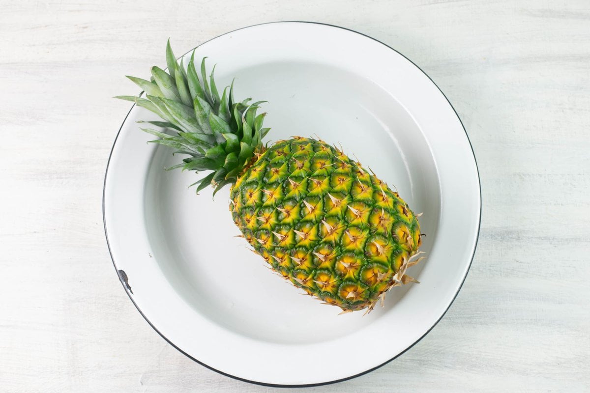 Whole fresh pineapple in a enamel bowl.