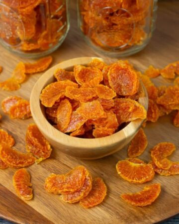 Dehydrated Mandarin orange slices in a small wooden bowl.