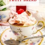 Large vertical closeup image of a serving of Million Dollar Fruit Salad recipe served in a vintage tea cup.