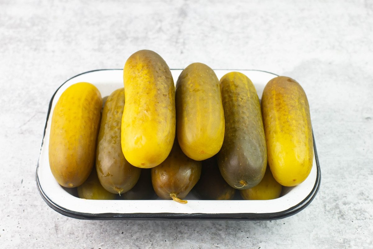 Jumbo dill pickles in an enamel tray.