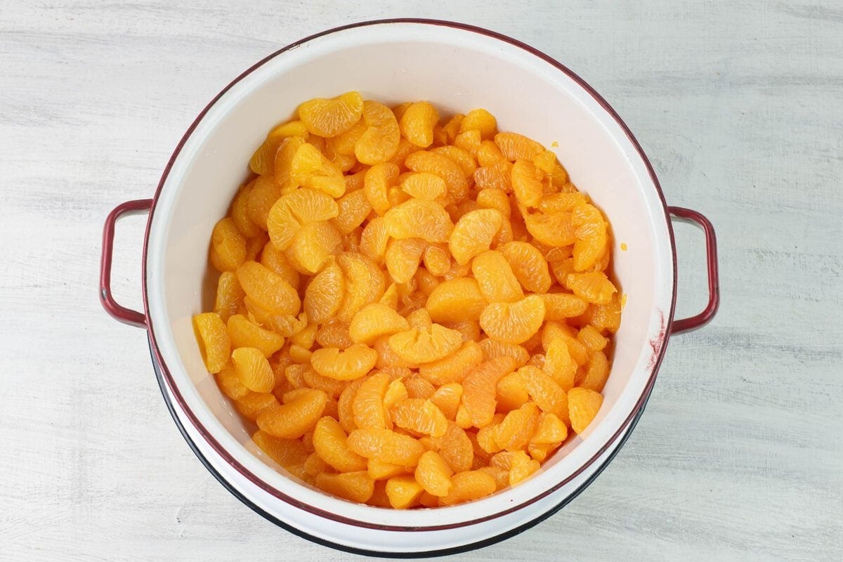 Drained canned mandarin orange sections in a large enamel colander.