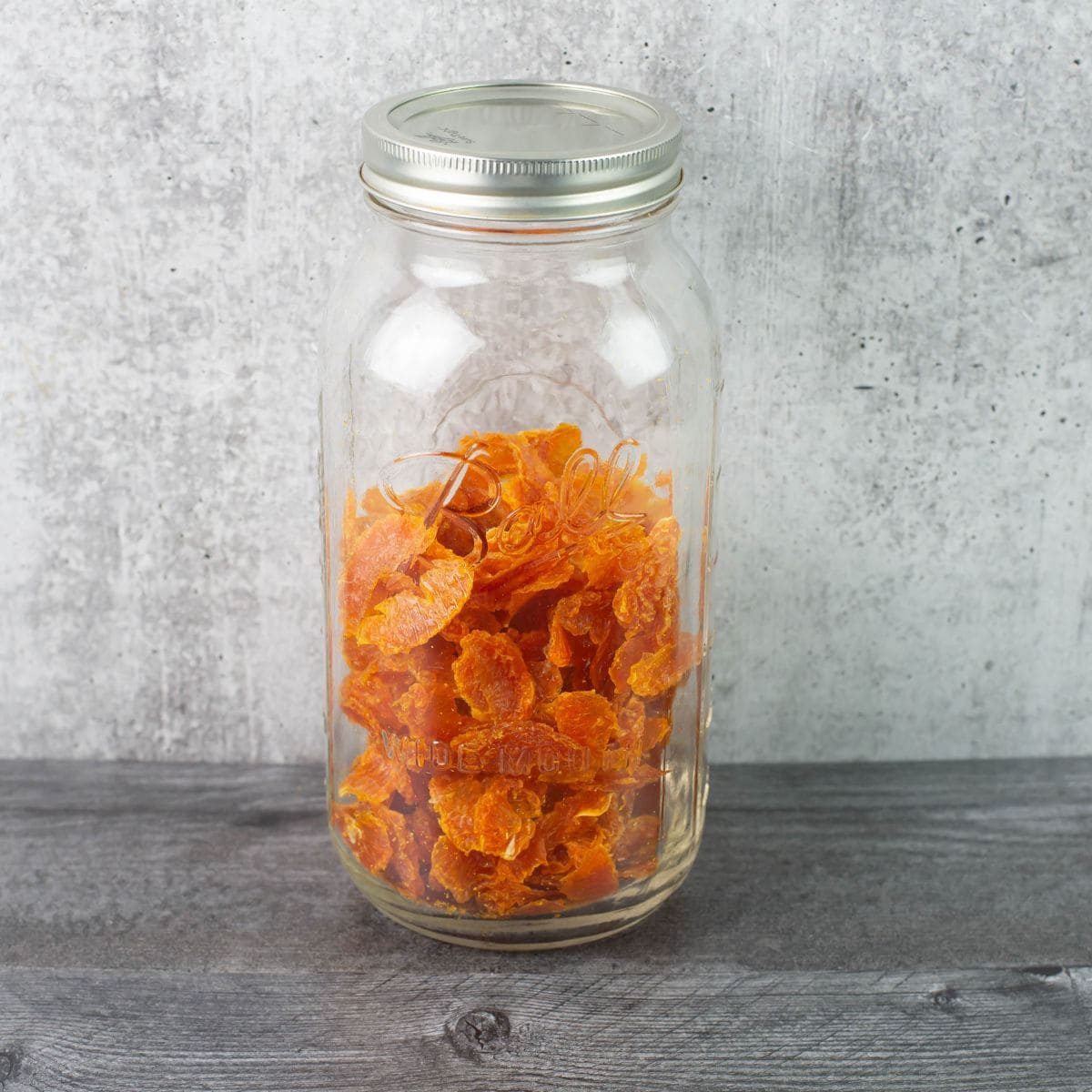 Large mason jar filled with dried fruit during the conditioning process.