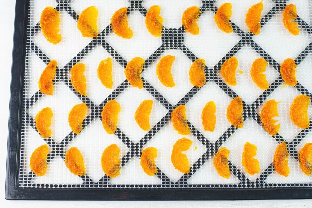 Dried orange segments on a dehydrator tray.