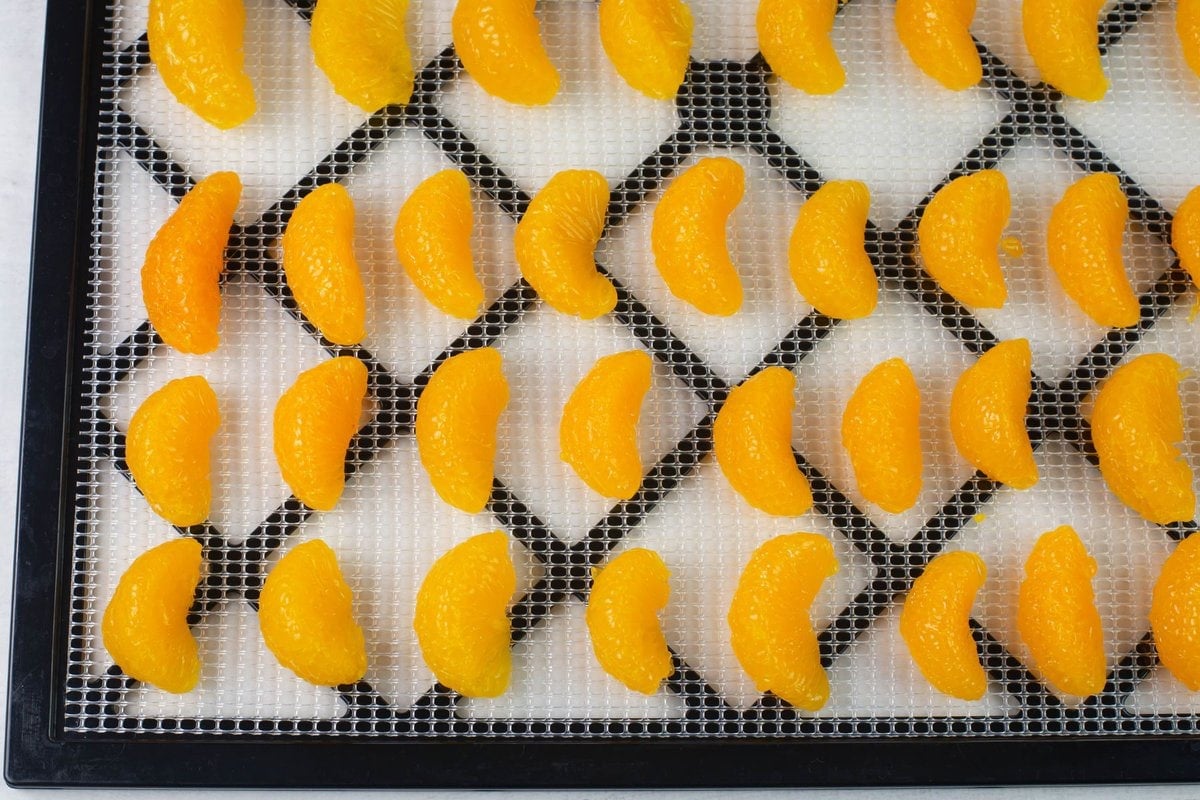 Canned orange segments on a dehydrator tray.