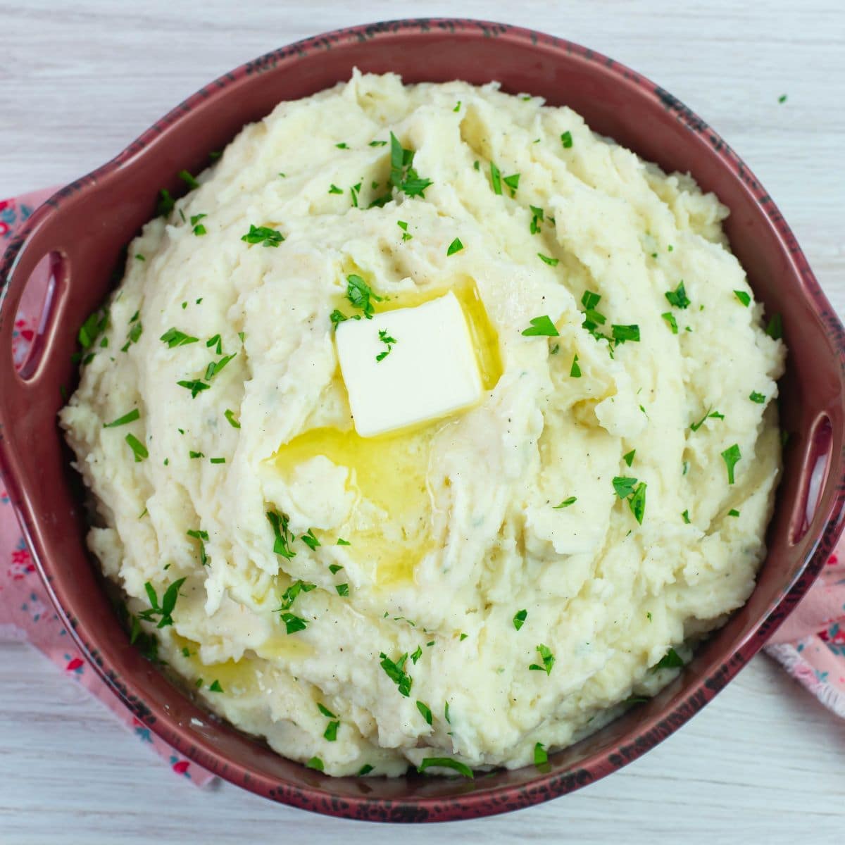 Serving bowl filled with Million Dollar Mashed Potatoes garnished with parsley.