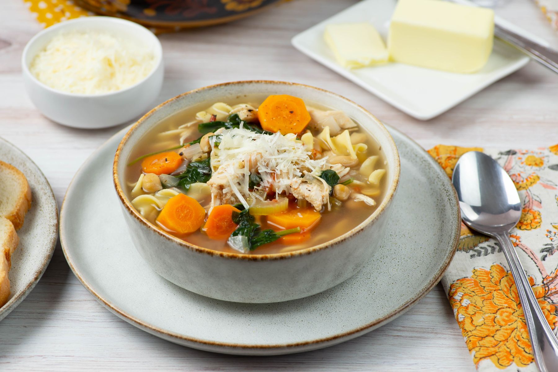 Parmesan topped bowl of chicken noodle soup.