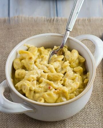 Bowl filled with Spicy Macaroni and Cheese with a fork on a placemat.