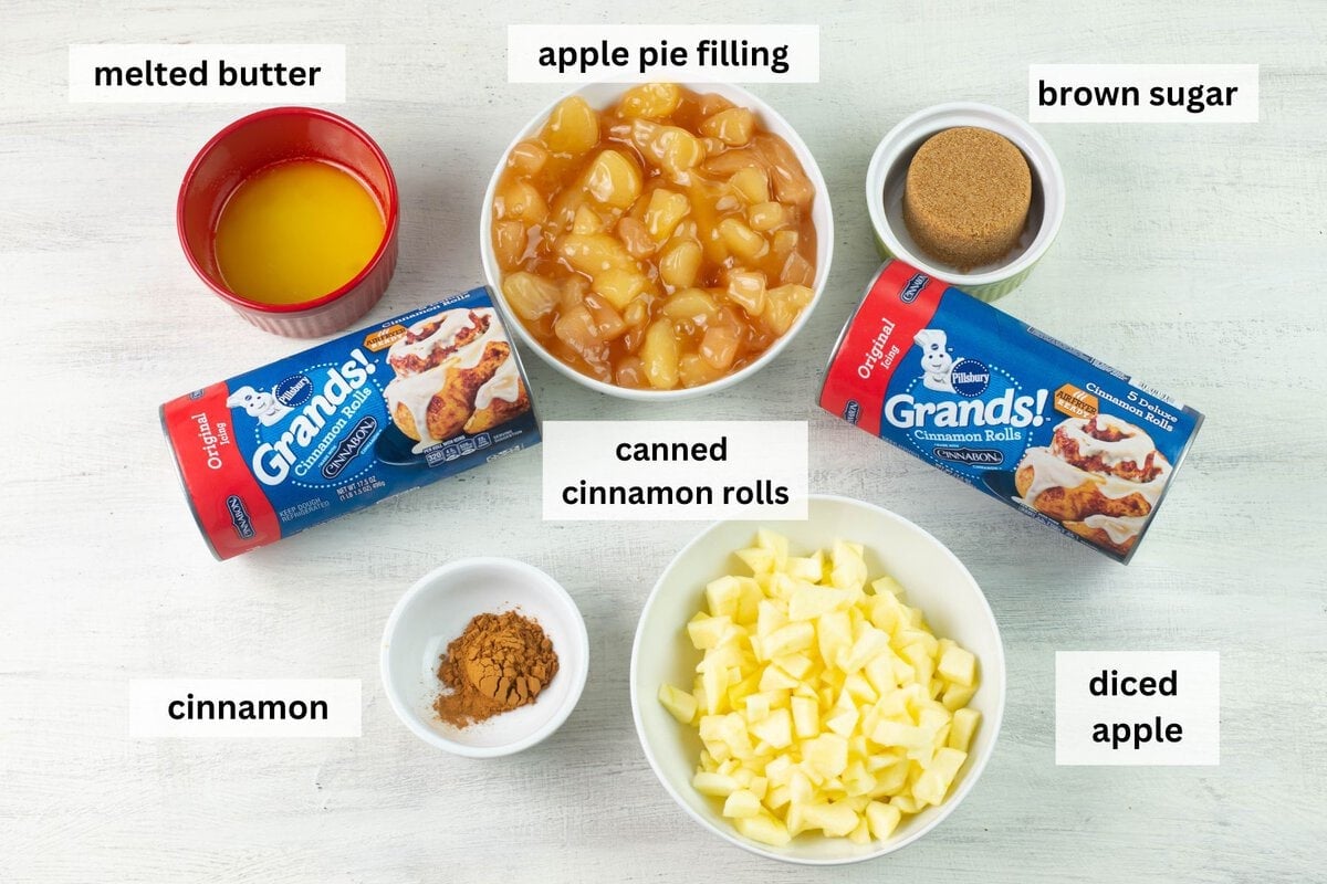 The breakfast casserole ingredients: apple pie filling,  melted butter, canned cinnamon rolls, brown sugar, cinnamon and diced apples needed to make an apple fritter casserole. 