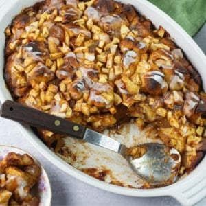 Serving apple fritter casserole from a baking dish with spoon.