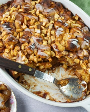 Serving apple fritter casserole from a baking dish with spoon.