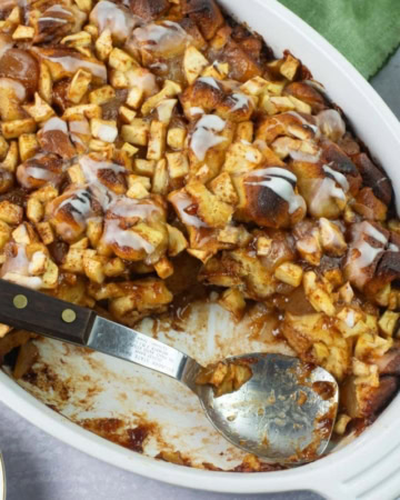 Serving apple fritter casserole from a baking dish with spoon.