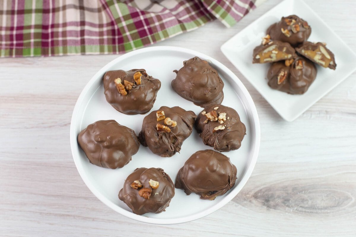 Chocolate dipped nut cluste4rs served on a dessert stand.