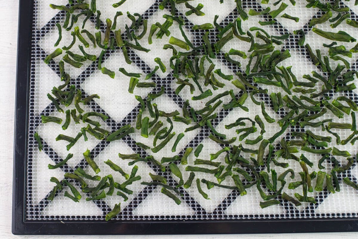 Dried green bean pieces on a dehydrating tray.