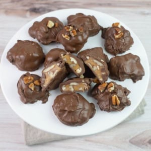 Pecan Caramel Clusters candy served on a white glass cake stand.