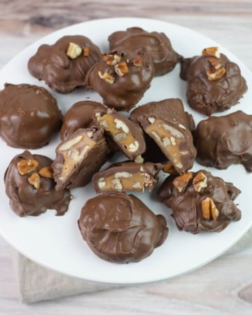 Pecan Caramel Clusters candy served on a white glass cake stand.