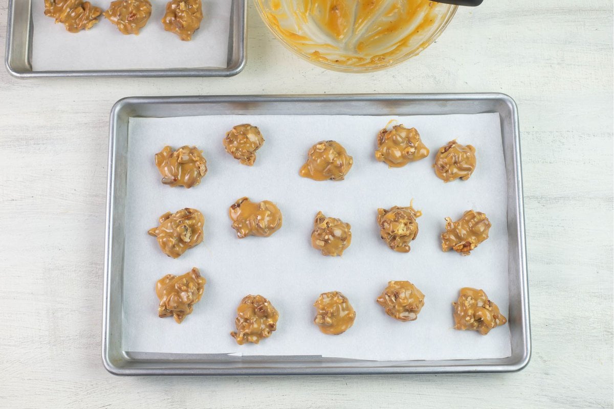 Mounds of pecan caramel filling hardening on a cookie sheet.