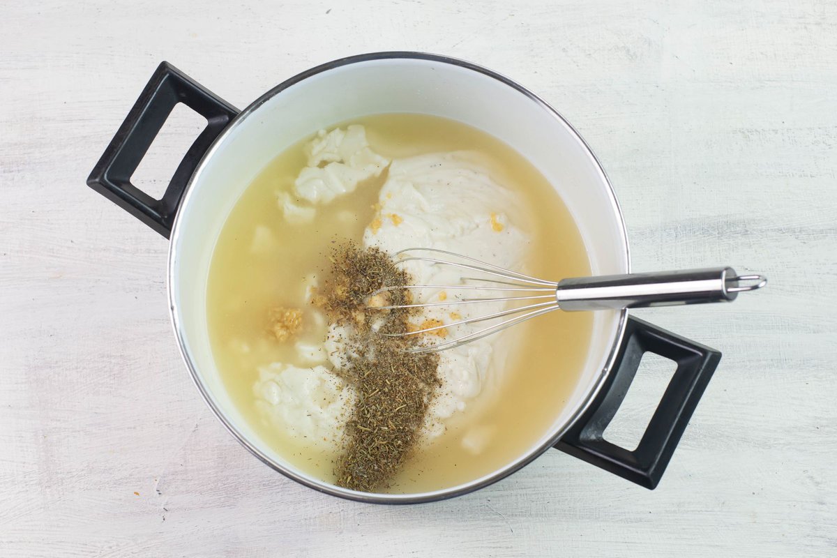 Whisking some soup ingredients together in a pot.