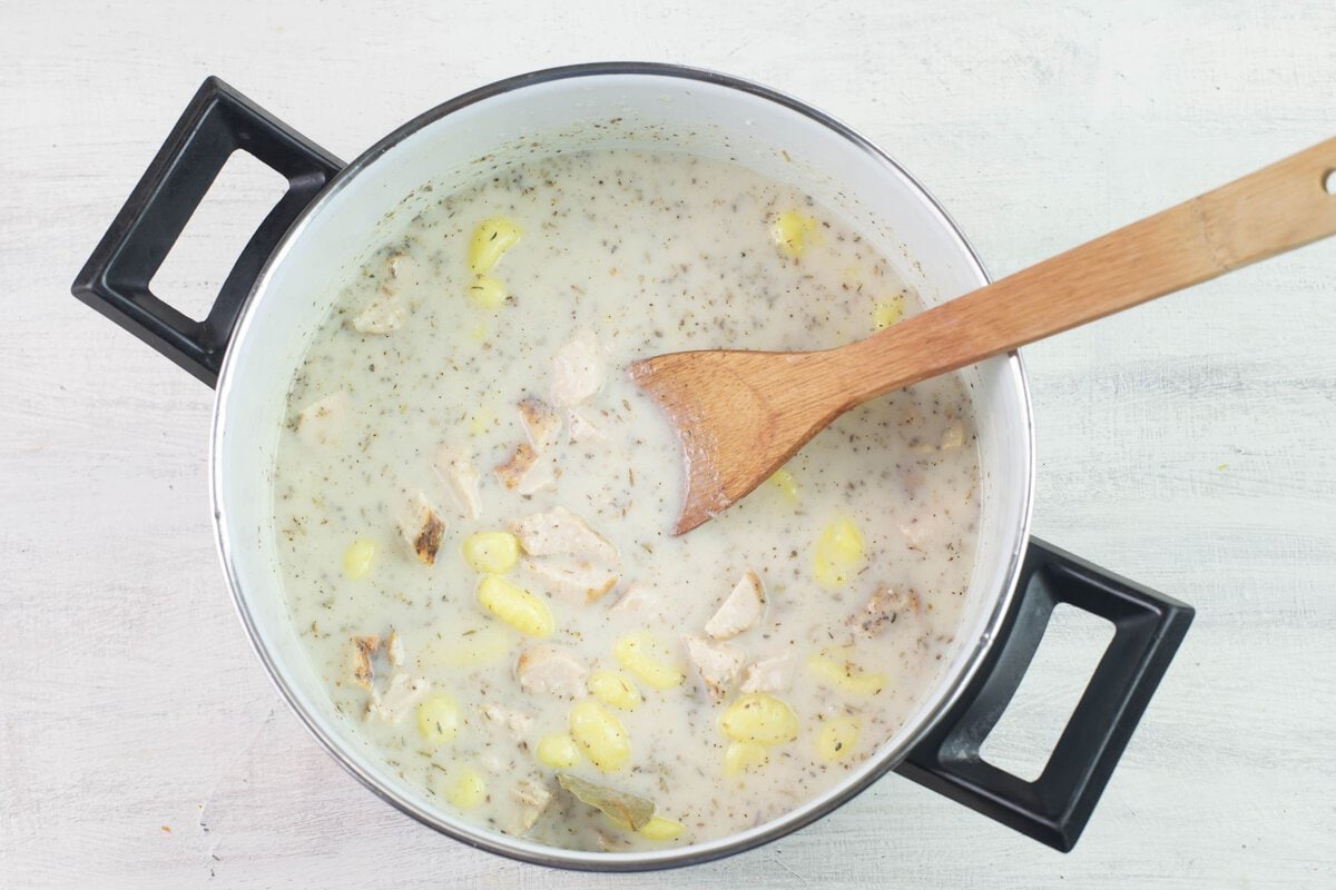 Mixing soup ingredients with wooden spoon in the pot.