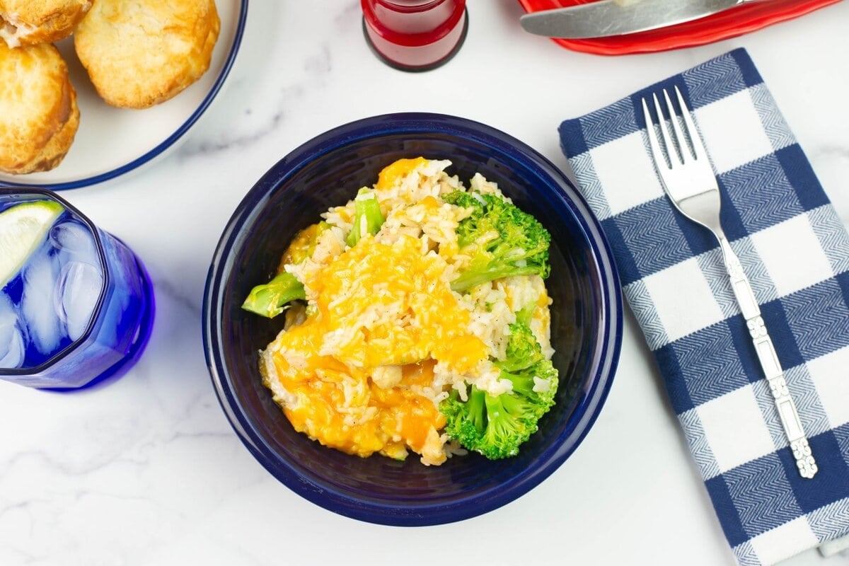 Overhead flat lay image of a serving bowl of the casserole with biscuits and butter on the table.