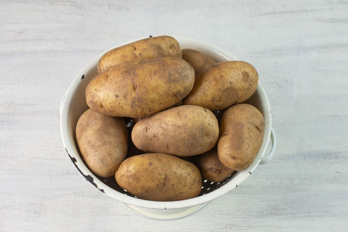 Whole uncut russet potatoes in a colander.