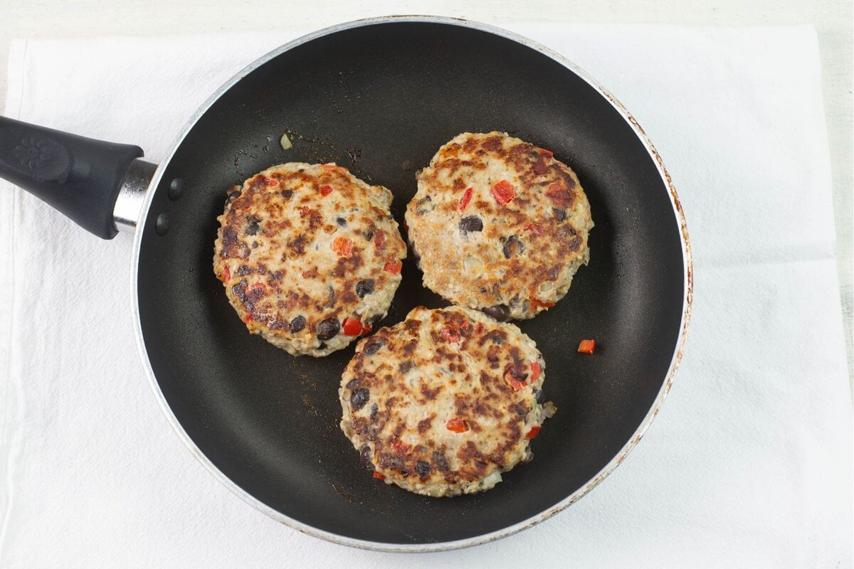 3 moist chicken burgers cooked in a skillet.