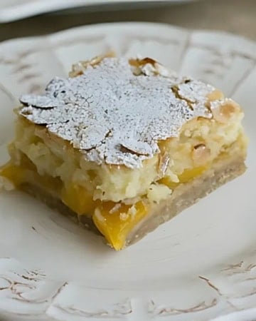 A slice of layered Peach Pie bars on a white plate.