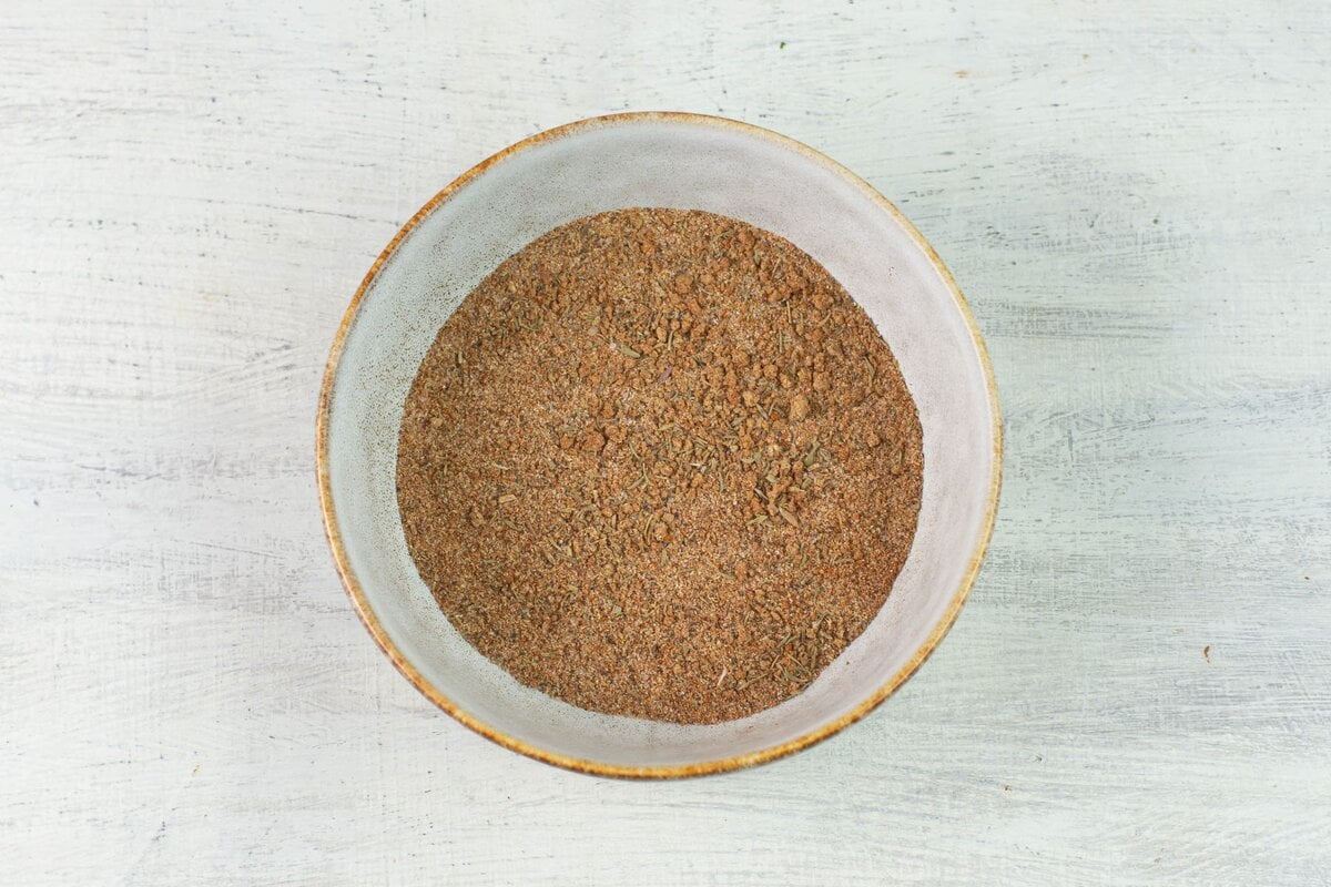A bowl of dried herbs and spices for pork seasoning blend.