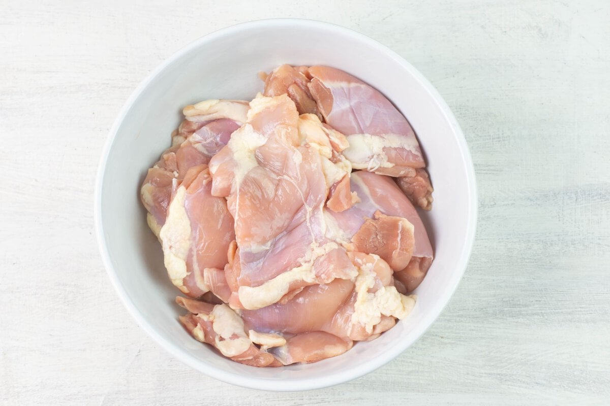 Boneless skinless chicken thighs in a white bowl.