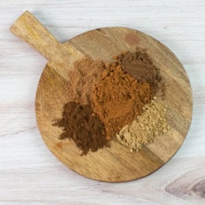 Wooden board with pumpkin pie spices in mounds.