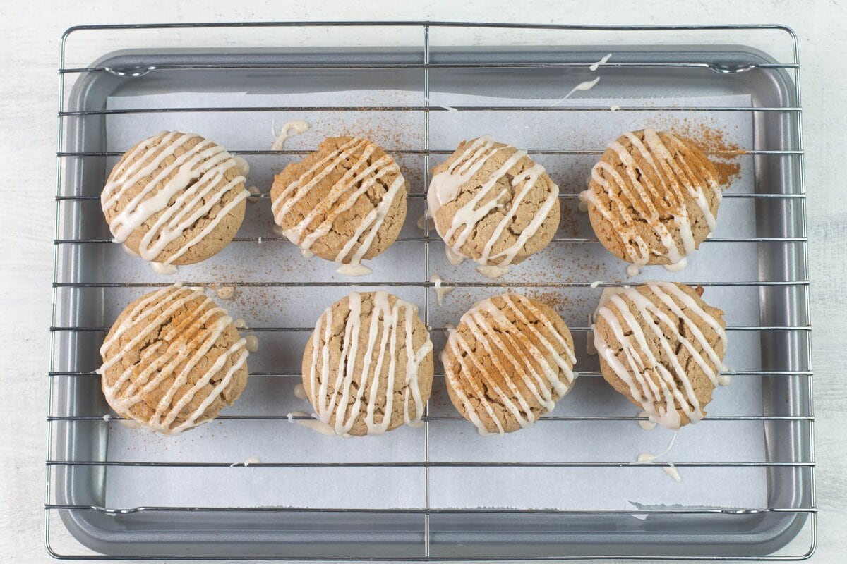 Powdered sugar icing drizzled cookies in a wire rack so the excess frosting can drip off.