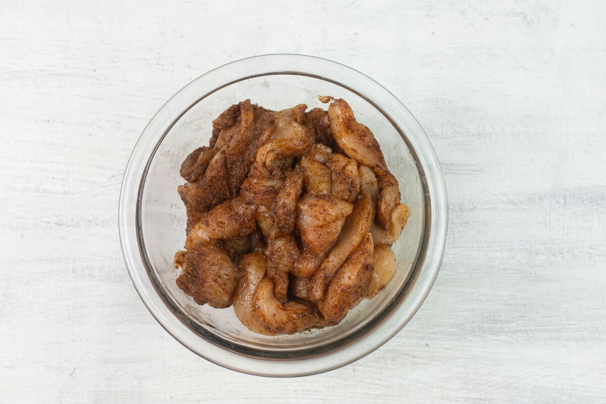 Sliced chicken covered in fajita seasoning in a bowl.