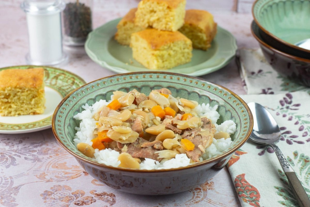 Cooked beans over rice in a bowl with cornbread on a plate.