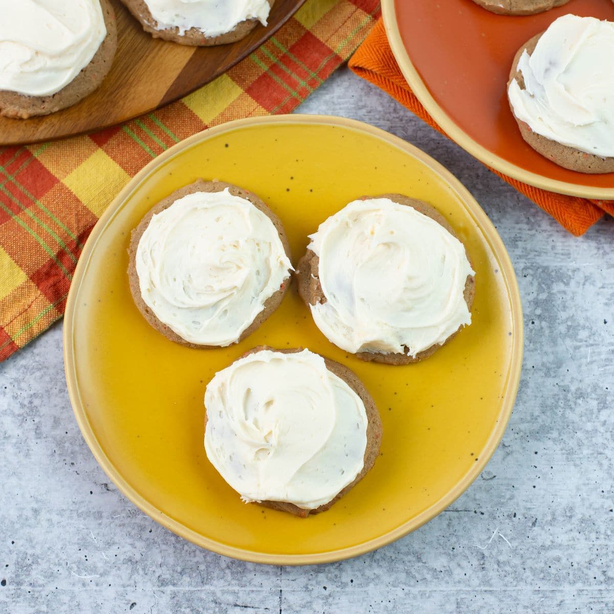 3 frosted Carrot Cake Cookies on a plate.