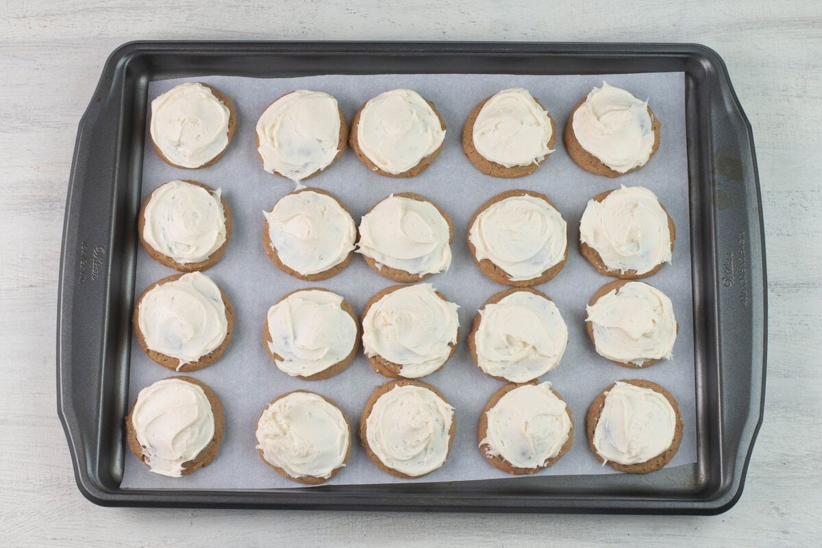 Frosted carrot cake cookies on a large cookie sheet.