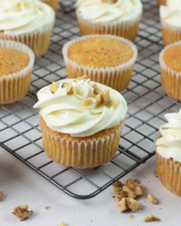 Cream Cheese frosted cupcakes on a wire rack.