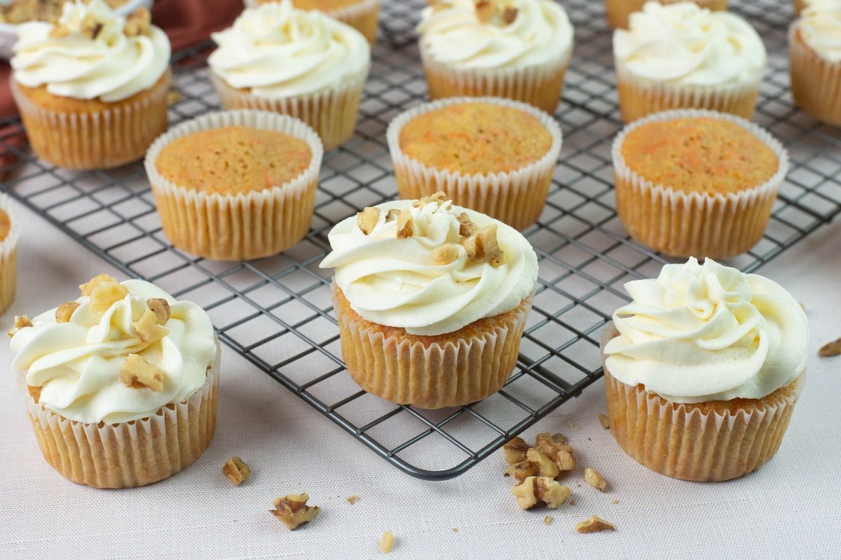 Cream Cheese frosted cupcakes on a wire rack.