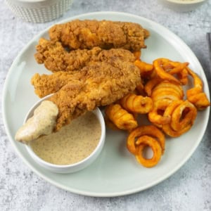 Dipping tenders into mustard sauce.