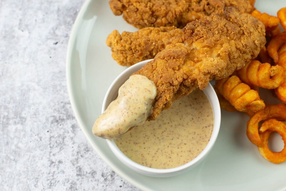 Crispy chicken tenders with a bowl of honey mustard.