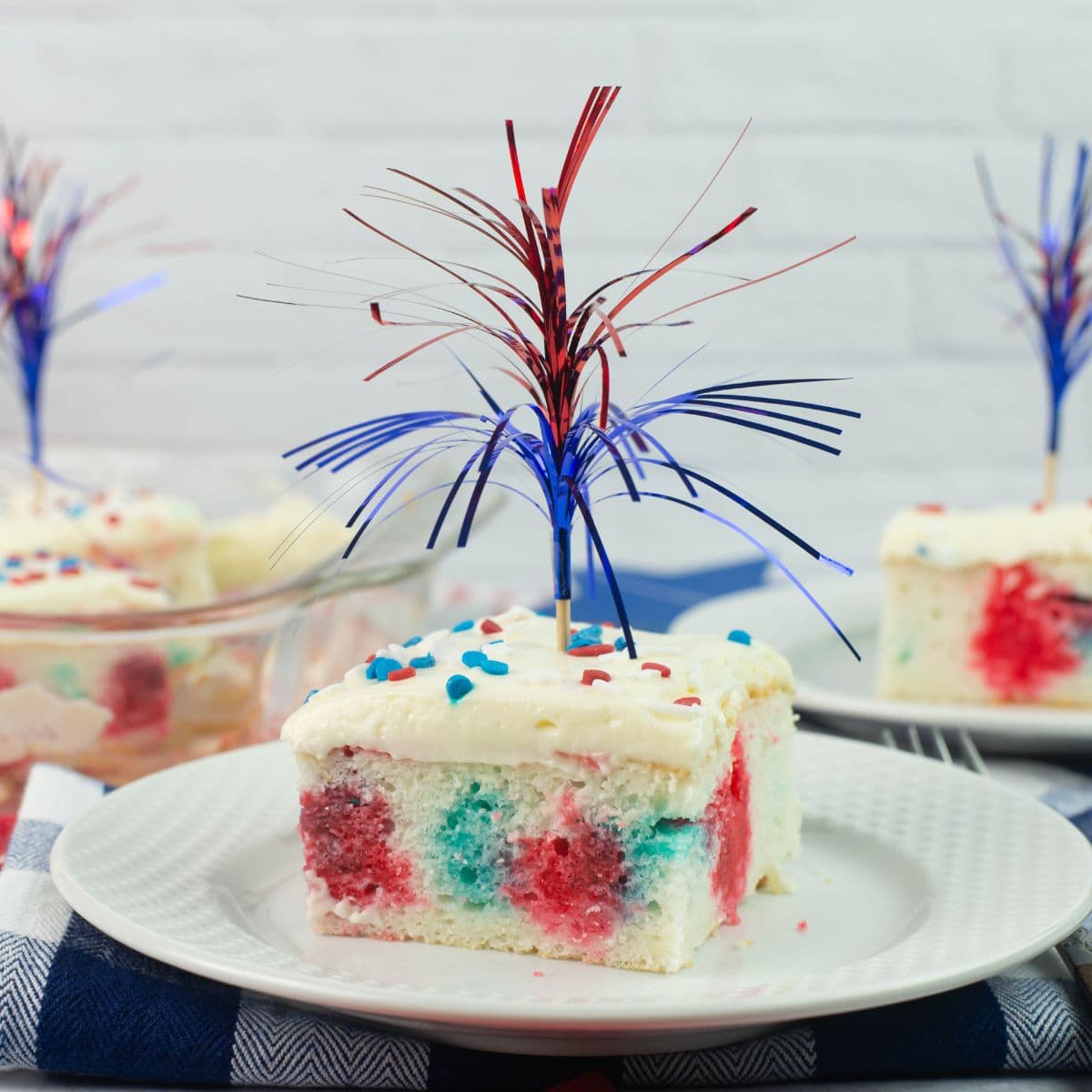 Red White and Blue Poke Cake cut into a square, decorated patriotic on a dessert plate.