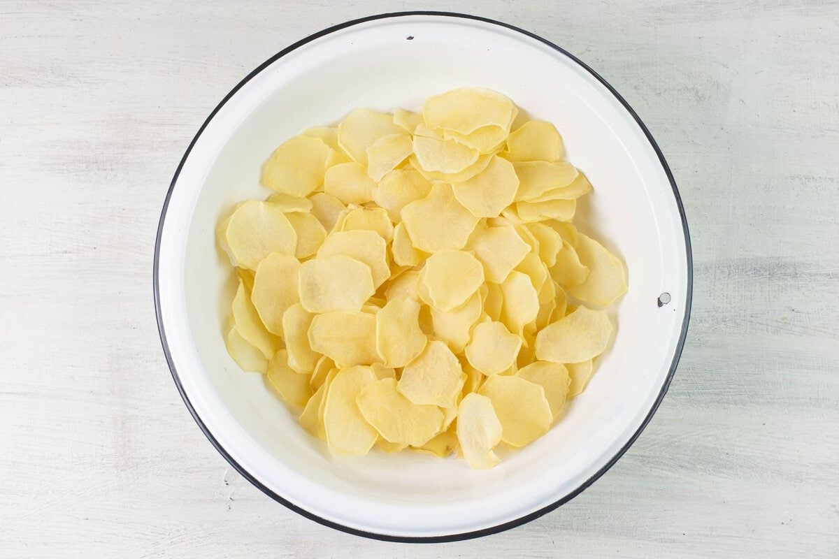 White enamel bowl filled with sliced and dried potatoes.