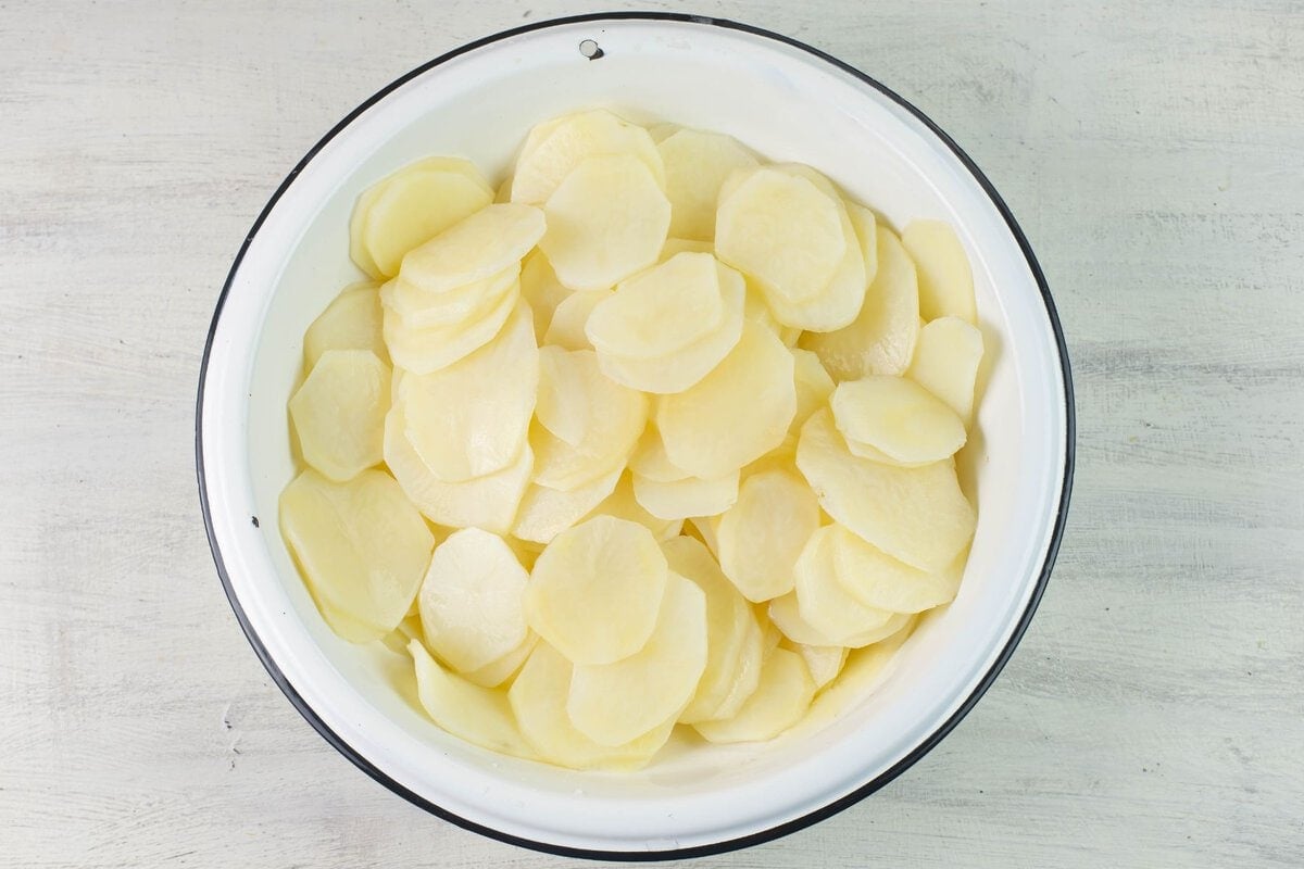 Blanched, cooled and drained potato slices in a bowl.